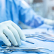 A surgeon with gloves touching their tools.